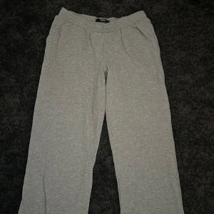 Grå mjukisbyxor från Bik Bok - Säljer ett par klassiska grå mjukisbyxor från Bik Bok med resår i midjan lågmidjad med raka ben. Tillverkade i mjukt och bekvämt material, perfekta för chill dagar. Enkel och stilren design utan synliga loggor eller detaljer.