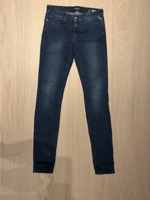Mörkblå skinny jeans från Replay - Snygga mörkblå skinny jeans från Replay med klassisk femficksdesign och diskreta slitningar. Jeansen har normal midja och smal passform hela vägen ner. Perfekta för dig som gillar en stilren och modern look.