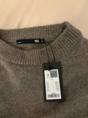 Brun stickad tröja från 157 - Mysig brun stickad tröja från 157 med rund halsringning och ribbade muddar vid ärmslut och nederkant. 