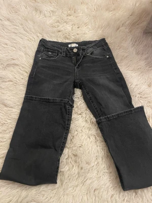 Svarta vida jeans med detaljer från Gina - Säljer ett par svarta jeans med vida ben och coola sömdetaljer över knäna. Jeansen har klassisk femficksdesign och knappstängning. Aldrig använda, så nya fast utan prislapp, endast testade. 