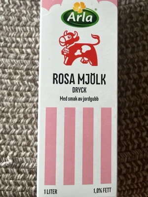 Arla Rosa Mjölkdryck Jordgubb (tom)  - En liter rosa mjölkdryck från Arla med smak av jordgubb. Förpackningen är vit med rosa detaljer och har en illustration av en röd ko. Perfekt till frukost eller som bas i olika recept. Innehåller 1,0% fett.