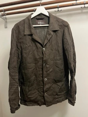 Mörk grön linnékavaj från Oscar Jacobson - Snygg mörk grön kavaj från Oscar Jacobson i luftigt linnetyg. Klassisk krage, 5 knappar framtill och två stora fickor. Perfekt för en avslappnad men stilren look. Passar dig som gillar tidlös design och naturliga material.