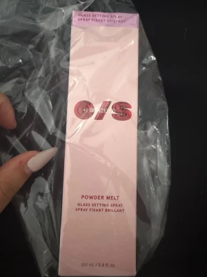O/S Powder Melt Glass Setting Spray - Säljer en Powder Melt Glass Setting Spray från O/S. Kommer i en snygg ljusrosa rektangulär förpackning med metallicröd logga. Innehåller 100 ml och är perfekt för att fixera makeup och ge en fräsch finish. Sprayen är enkel att använda och passar alla hudtyper.