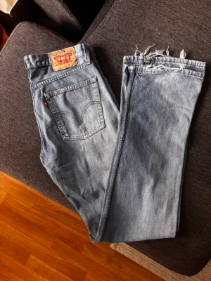 Levi's 518  ljusblå jeans - Säljer ett par klassiska ljusblå Levi's jeans med raka ben och, fransiga benslut. Modell 518, storlek 36*36 Tillverkade i slitstark denim, perfekta för en trendig look.