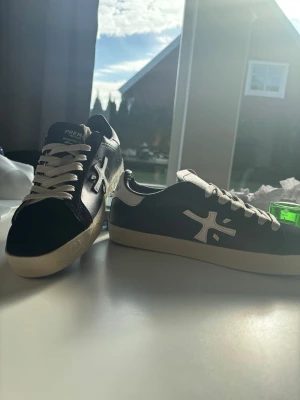 Premiata sneakers svart/vit läder - Snygga sneakers från Premiata i svart och vitt läder med vit sula och vita skosnören. Klassisk låg modell med tydlig logga på sidan och texten 'Premiata Prmt Edition' på hälen. Perfekta för dig som gillar stilrena och trendiga skor.