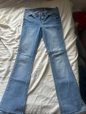 Bootcut jeans från Calvin Klein - Snygga ljusblå bootcut jeans från Calvin Klein med klassisk femficksmodell och subtila slitningar. Jeansen har broderade bakfickor och är tillverkade i mjuk denim med lite stretch för extra komfort. Perfekta för en avslappnad och trendig look. Jeansen har några defekter! Några små missfärgningar på framsidan och vid byxbenet och samt lite slitet! Midjelängden är samma som mina true religion joey low rise flare! storlek 25/0 som är runt xxs-xs. Skriv gärna vid frågor!
