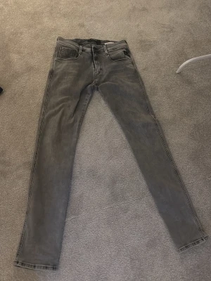 Grå skinny jeans från Replay - Säljer ett par gråa skinny jeans från Replay, modell Hyperflex. Jeansen har klassisk femficksdesign, normalhög midja och stretchigt material för extra komfort. Snygg tvättad look och smal passform som sitter tight hela vägen ner.