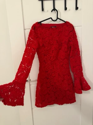Röd blommig spetsklänning med volangärm - Superfin röd kortklänning från Gina Tricot med 3D-blommor över hela tyget. Klänningen har långa ärmar med volang vid ärmslut och är tillverkad i spetsliknande material. Perfekt för dig som vill sticka ut med en färgstark look! Pris kan diskuteras 