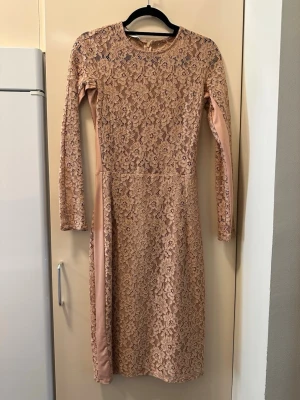 Beige spetsklänning med lång ärm från mango  - Elegant beige långklänning med blommigt spetsmönster och långa ärmar. Klänningen har rund halsringning och är helfodrad med mjukt tyg undertill. Perfekt för dig som gillar romantisk och stilren look. Obs klänningen är genomskinlig vid överdelen och har en inbyggd kjol vid underdelen av klänningen!🩷