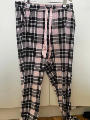 Rutiga pyjamasbyxor från new Yorker - Mysiga pyjamasbyxor i rosa och svart rutigt mönster.  Materialet är som en filt typ. Byxorna har resår i midjan och ett rosa satinband för justering. Korta i storleken.