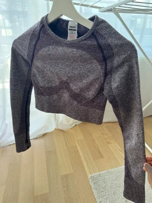 Lila cropped träningströja Gymshark - Cropped långärmad träningströja från Gymshark i melerad lila och grå färg. Perfekt för gymmet eller annan träning. Köpt för några år sedan men endast använd 2ggr.