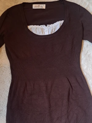 Brun tröja med vit spetsdetalj - Så fin och mysig brun tröja med fin vit detalj. Tröjan är lång och i jättebra skick. I mitten av tröjan finns ett tightare område vilket ger en fin siluett. Pris kan alltid disskuteras!💞💕