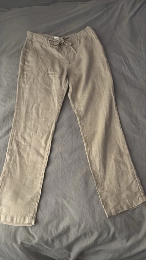 Beige linnebyxor från GANT - Snygga beige linnebyxor från GANT som är i storlek M. Byxorna har klassiska fickor och är tillverkade i ett lätt och luftigt linnematerial som är perfekt för varma dagar.   Pris kan diskuteras! 