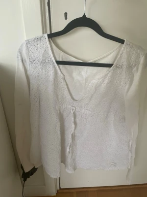 Vit blus med spetsdetaljer och v-ringning - Säljer en luftig vit blus med v-ringning och långa ärmar. Blusen har fina spetsdetaljer framtill och knytband under bysten. Perfekt för dig som gillar romantisk och bohemisk stil.