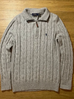 Grå kabelstickad half zip  Polo Ralph Lauren M - Kabelstickad grå half zip från Polo Ralph Lauren med halv dragkedja och broderad marinblå logga på bröstet. Kan dock inte frakta varan inom kommande 7 dagarna!   Pris kan diskuteras!  