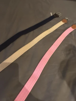 3-pack flätade bälten i olika färger - Säljer ett set med tre flätade bälten i färgerna rosa, beige och svart. Bältena har snygga detaljer i brunt skinn vid spännet och klassiskt silverfärgat spänne. Perfekt accessoar för att lyfta din outfit. ALLA TRE FÖR 249!!