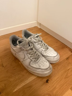 Vita Nike Air Force 1 sneakers - Klassiska vita Nike Air Force 1 sneakers med lågt skaft och perforerad tå. Skorna har en chunky sula och är tillverkade i läder med textildetaljer på insidan. Perfekta för en clean och stilren look. Använda därefter låg pris 
