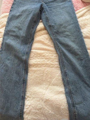 Blå raka jeans i klassisk modell - Säljer ett par blå jeans med rak passform och klassisk femficksdesign. Jeansen har normal midja och är tillverkade i ett slitstarkt denimtyg. Perfekta för en avslappnad och tidlös stil.