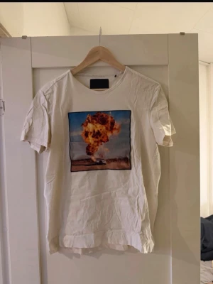 LIMITATO TRÖJA - Cool vit t-shirt med ett stort tryck av en explosion på bröstet. T-shirten har klassisk passform och korta ärmar. Perfekt för dig som vill sticka ut med ett unikt motiv.