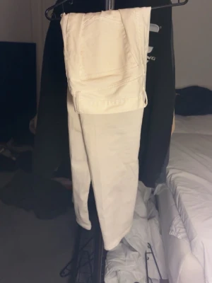 Vita raka jeans - Säljer ett par vita jeans med rak passform och klassiska bakfickor. Jeansen har en stilren look och är perfekta för dig som vill ha en clean och fräsch stil. Materialet känns som bomull med lite stretch för extra komfort. nån enstaka fläck här och där