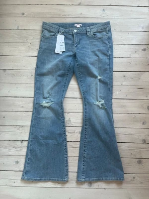 Ljusblå oanvända bootcut jeans! - Snygga ljusblå bootcut jeans med slitningar på båda benen och broderade detaljer på bakfickorna. Aldrig använda, bara testade!