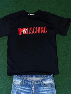 Moschino x H&M tröja  - 🔥  Moschino x H&M t-shirt – perfekt till sommaren Säljer en riktigt snygg Moschino x H&M tröja i svart med ikonisk MTV/Moschino-logga framtill. Väldigt clean och stilren modell som passar perfekt till sommaren.  💸 Nypris cirka 900 kr – säljs billigt vid snabb affär. 📏 Storlek S men passar M bättre  ✨ Mycket fint skick. 👌 Skön passform och enkel att matcha med jeans, shorts eller cargos.