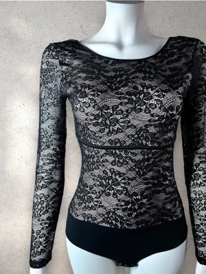 Intimissimi  spetsbody med lång ärm - Snygg svart body i genombruten spets med blommönster och långa ärmar. Rund halsringning och markerad midja. Stretchigt material som sitter tight mot kroppen. Perfekt för att skapa en trendig och elegant look. #intimissimi