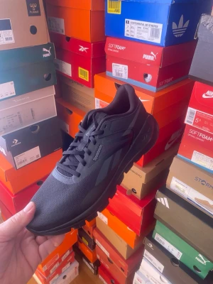 Svarta Reebok sneakers - Snygga helsvarta sneakers från Reebok med klassisk låg profil och diskret logga på sidan. Skorna har en sportig design med mesh och syntetmaterial för bra andningsförmåga och komfort. Perfekta för dig som gillar stilrena och mångsidiga sneakers.