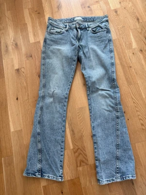 Ljusblå bootcut jeans - Säljer ett par ljusblå bootcut jeans från Gina med snygga sömmar på bakfickorna. Jeansen har en avslappnad passform och är tillverkade i denim med lätt tvättad look.