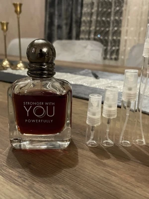 Emporio Armani Stronger With You Powerfully  - Emporio Armani Stronger With You Powerfully är en parfym med mörkröd vätska i en elegant, fyrkantig glasflaska med rund, metallisk kork. Flaskan har stilren design och tydlig logotyp framtill. Perfekt för dig som gillar exklusiva och moderna dofter.