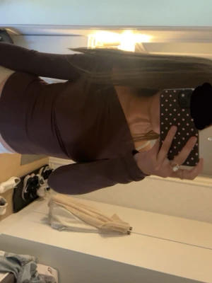 Brun offshoulder topp med lång ärm - Säljer en brun offshoulder topp med lång ärm och tight passform. Toppen har en snygg asymmetrisk skärning över axlarna och är gjord i ett stretchigt material som sitter bekvämt. Perfekt att matcha med jeans eller kjol.