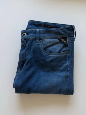 Replay Marinblå Jeans - Snygga blå jeans från Replay med klassisk femficksdesign och diskret Replay-logga på fickan. Jeansen har kontrastsömmar och en cool bakficka med broderad detalj. Materialet är mjukt denim som ger en skön passform och stilren look. Storleken är W30/L32