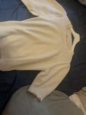 Beige stickad tröja från ONLY - Snygg beige/vit stickad tröja från ONLY med rund halsringning och kortare ärmar. Tröjan har en enkel och stilren design, perfekt att matcha med jeans eller kjol. Mjuk och skön kvalitet som känns lyxig mot huden.