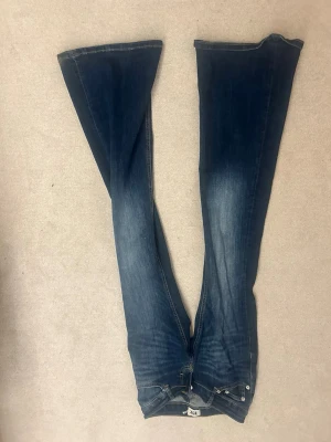 Blå bootcut jeans med utsvängda ben - Säljer ett par blå bootcut jeans med riktigt utsvängda ben och snygg tvätt. Jeansen har klassisk femficksdesign och dragkedja. Perfekta för dig som gillar retrostil och vill ha ett par jeans som sticker ut.