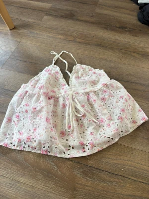 Blommig spetslinnetopp från SHEIN - Söt blommig linnetopp från SHEIN i vitt med rosa blommor. Toppen har spetsdetaljer, broderade hålmönster och smala axelband. Perfekt för sommaren