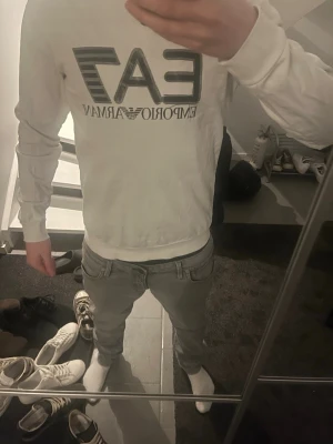 Vit EA7 Emporio Armani sweatshirt - Säljer en vit sweatshirt från EA7 Emporio Armani med stor logga framtill. Tröjan har rund halsringning och långa ärmar. Perfekt för dig som gillar stilrena och klassiska plagg med tydlig branding. De är storlek s-m jag på bilden är 178 och så sitter den på mig. Hör av er för mer frågor!🤗