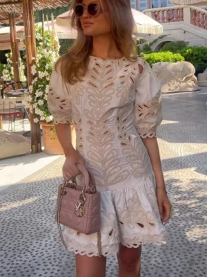 Vit broderad kortklänning från Maje - Superfin vit kortklänning från Maje med broderade detaljer och puffärmar. Klänningen har ett vackert mönster, rund halsringning och volangkant nedtill. Perfekt för sommardagar och har en luftig, elegant känsla. Perfekt till studenten 