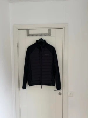 Svart pufferjacka från Peak Performance äkta! - Snygg svart pufferjacka från Peak Performance med quiltad framsida och dragkedja. Jackan har lång ärm och diskret logga på bröstet samt ärmen. Perfekt för kyliga dagar och enkel att matcha med olika outfits.