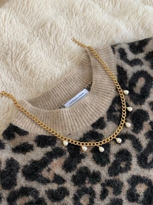 Guldhalsband med pärldetaljer - Snyggt halsband i guldfärgat rostfritt med kedja och små hängande pärlor. Perfekt för att lyfta vilken outfit som helst med en trendig touch. Klassisk design som passar till många stilar.