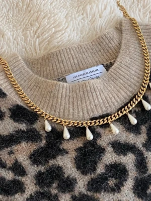Guldfärgat halsband med droppformade pärlor - Snyggt halsband i guldfärgad rostfritt med kedja och hängande droppformade pärlor. Perfekt för att ge din outfit en trendig och elegant touch. Halsbandet har en chunky kedja och pärlorna ger en lyxig känsla.