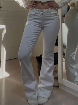 bootcut jeans  - Snygga vita bootcut jeans med hög midja och klassiska fickor både fram och bak. Jeansen har en figurnära passform upptill och utsvängda ben, vilket ger en trendig siluett. Perfekta att styla med crop tops eller hoodies.
