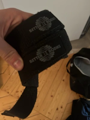 Svarta lyftremmar Better Bodies - Säljer ett par svarta lyftremmar från Better Bodies. Perfekta för gymmet när du vill maxa greppet vid tunga lyft. Remmarna är i slitstarkt tygmaterial och har logga tryckt i vitt. Snygg och funktionell accessoar för styrketräning.