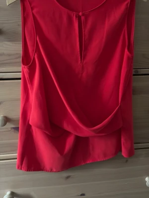 Röd ärmlös topp från Zara Basic - Snygg röd ärmlös topp från Zara Basic med draperad front och rund halsringning. Perfekt att styla med jeans eller kjol för en trendig look. Lätt och luftig känsla, passar bra till varmare dagar.
