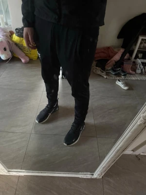 Nike Air Max 270 svarta sneakers - Svarta Nike Air Max 270 sneakers med vit sula och tydlig Air Max-dämpning i hälen. Snygg design med mesh-överdel och vita Nike-loggor på sidan och tån. Perfekta för en sportig och trendig look.