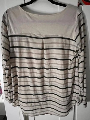 Randig långärmad topp i bomull - Snygg långärmad topp med svartvita horisontella ränder och rund halsringning. Tillverkad i mjuk bomull, perfekt för en avslappnad stil. Passar bra till jeans eller kjol för en enkel look.
