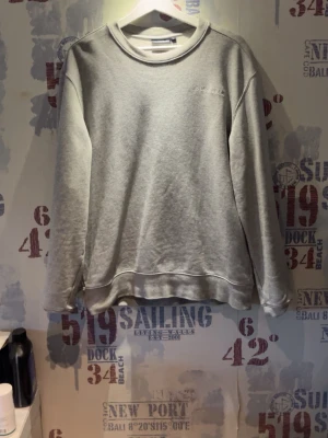 Grå sweatshirt från J.Lindeberg - Säljer en stilren grå sweatshirt från J.Lindeberg. Tröjan har rund halsringning, långa ärmar och diskret broderad logga på bröstet. Tillverkad i mjukt material som passar perfekt till jeans eller joggers.