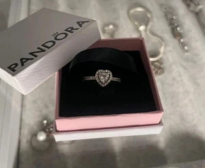Pandora silverring med hjärta - Snygg silverring från Pandora med ett glittrande hjärta i mitten, omgiven av små stenar längs hela ringen. Ringen har en elegant och romantisk design som verkligen sticker ut. Perfekt att ge till present till någon speciell💕💕