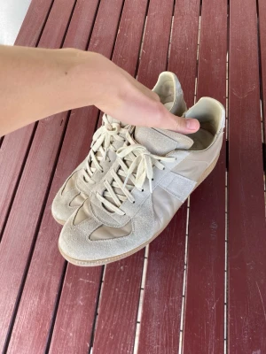 Maison Margiela GATs  - Säljer ett par stilrena och eftertraktade Maison Margiela GATs i beige. Använda med bruksspår som ger en snygg worn-in look. Fortfarande väldigt fina på fot och med mycket användning kvar.  Tidlös och exklusiv sneaker med premiumkänsla.