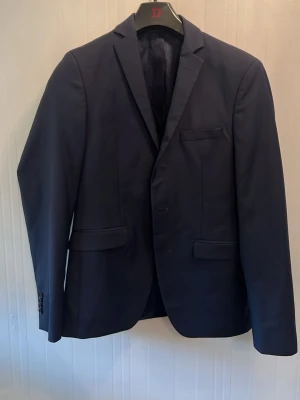 Mörkblå kavaj från Vitale Barberis - Stilren mörkblå kavaj från Vitale Barberis Canonico med klassisk passform och snygga fickdetaljer. Tillverkad i Italien av exklusivt tyg, helfodrad och med diskreta knappar vid ärmslut. Perfekt för en dressad look.