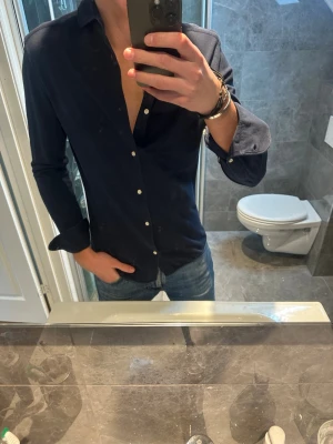 Mörkblå skjorta - Snygg mörkblå skjorta i mjukt mesh material passar perfekt till både vår och sommar. Skjortan är i riktigt bra skick och har inga defekter. Jag på bilden är 188cm och bör storlek M. Hör av er vid frågor eller närmare bilder på plagget:)